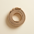 Anais sand woven belt with a gold buckle, coiled on a cream studio backdrop