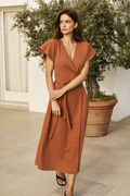 The Positano wrap dress in terracotta on a sunny terrace