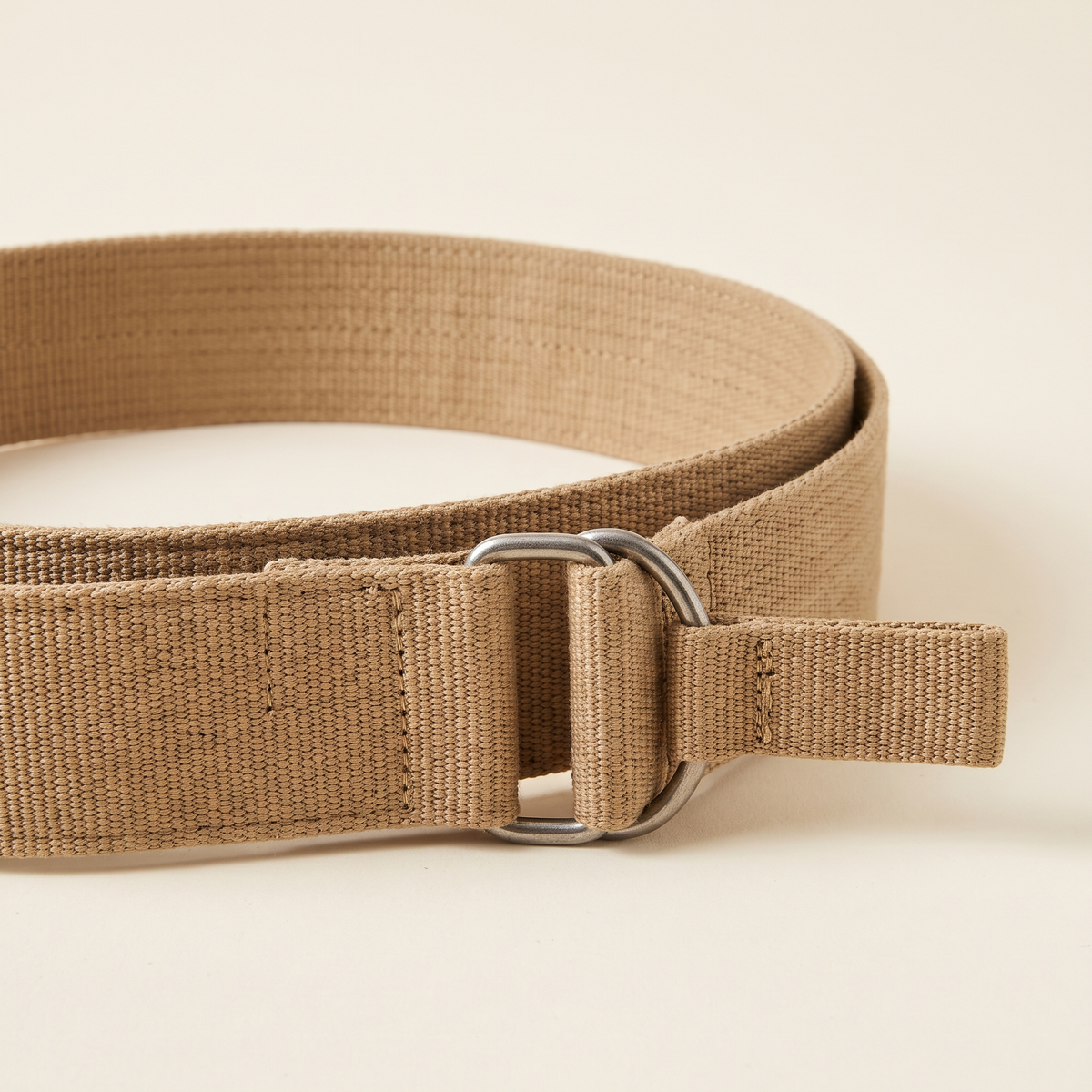Ophelie belt buckle and strap detail on a cream studio backdrop