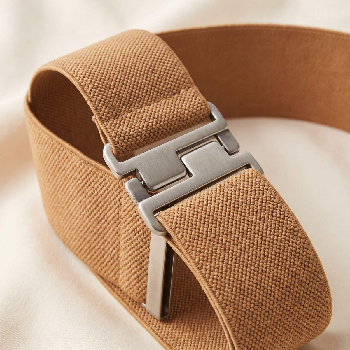 Veronique belt buckle and strap detail on a cream studio backdrop